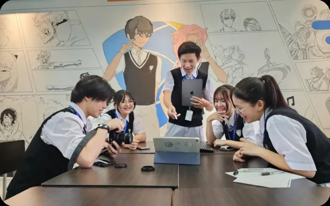 Grade 11 students gathered around a tablet in a mural-covered classroom